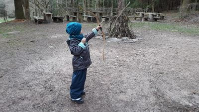 boy aiming with bow in the woods